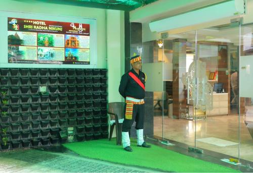 a man in uniform standing in a store window at Hotel Shri Radha Nikunj - Opposite Prem Mandir in Vrindāvan