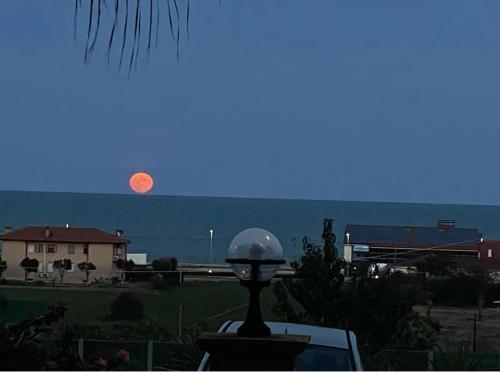 a full moon rising over the ocean with a house at Casa vacanze Levata del sole in Porto Potenza Picena