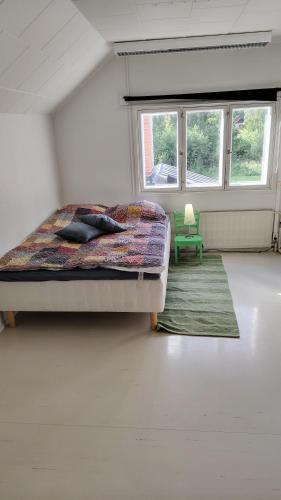 a bedroom with a bed and a green chair at Vanha hirsikoulun yläkerta in Kankaanpää