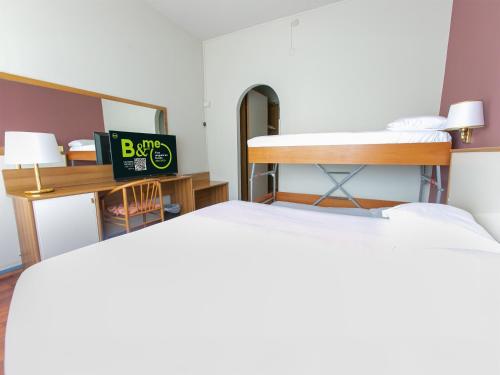 a room with two beds and a desk with a mirror at B&B HOTEL Riviera Celle Ligure in Celle Ligure