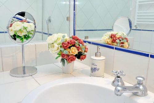 a bathroom sink with a mirror and a vase of flowers at Terrazze Navona in Rome