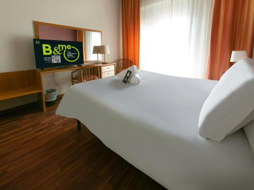 a bedroom with a white bed with a tv and a window at B&B HOTEL Riviera Celle Ligure in Celle Ligure
