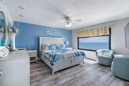 a bedroom with blue walls and a bed and a window at Beachfront 3 Bed, 3 Bath Condo, Balcony & Pool in Daytona Beach Shores