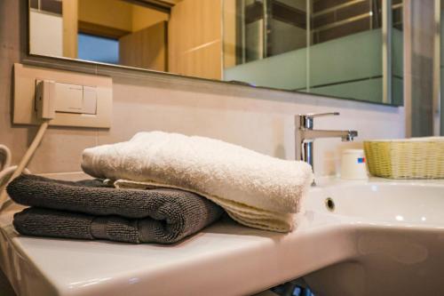 a pile of towels sitting on a bathroom sink at Riflessi D'acqua in Lavena Ponte Tresa