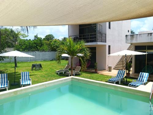 a swimming pool with chairs and umbrellas next to a building at El Turix Bacalar in Bacalar