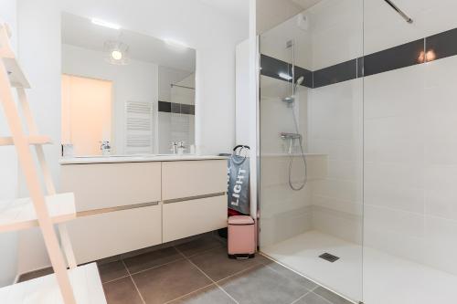 baño con ducha a ras de suelo junto a un espejo en Appartement Lumineux avec Terrasse, en Seignosse