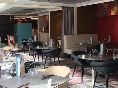 a restaurant with tables and chairs and wine glasses at Mercure Amiens Cathédrale in Amiens