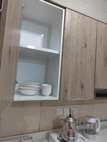 a kitchen cabinet with bowls and plates in it at وادي العقيق203 in Al Madinah