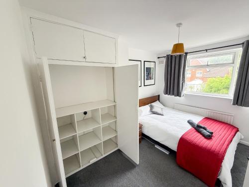 a small bedroom with a bed and a red suitcase at Bassetts House - Contractor ready! in Farnborough