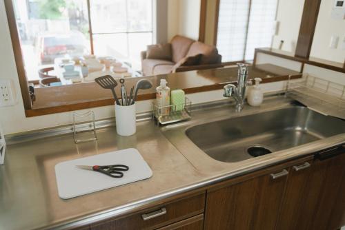 a kitchen sink with a pair of scissors on a counter at Kumamoto Airport Villa 5 mins from Kumamoto Airport in Nishiharamura