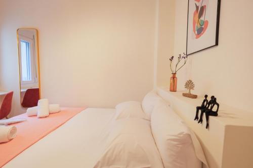 a white bedroom with a bed with two statues on it at AG Living One in Thessaloniki