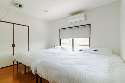 two beds in a white room with a window at Kumamoto Airport Villa 5 mins from Kumamoto Airport in Nishiharamura