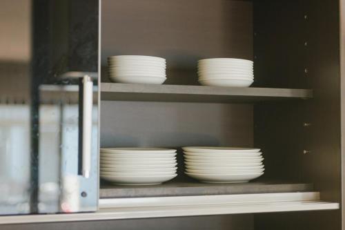 a shelf filled with white plates and bowls at Kumamoto Airport Villa 5 mins from Kumamoto Airport in Nishiharamura