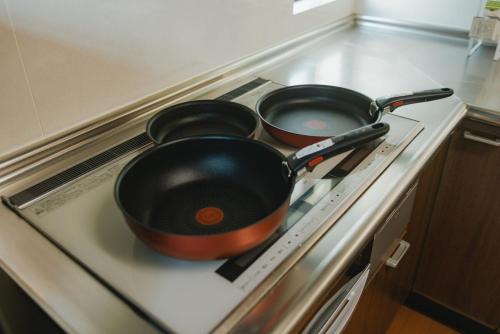 two pans sitting on top of a stove at Kumamoto Airport Villa 5 mins from Kumamoto Airport in Nishiharamura