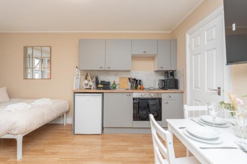 a kitchen with white cabinets and a dining table at Open Mind Property - Studio for 4 Guests - Parking in Bournemouth