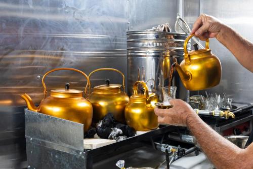 Een man is bezig een aantal gouden theepotten klaar te maken. bij Teba Karbala Hotel in Karbala
