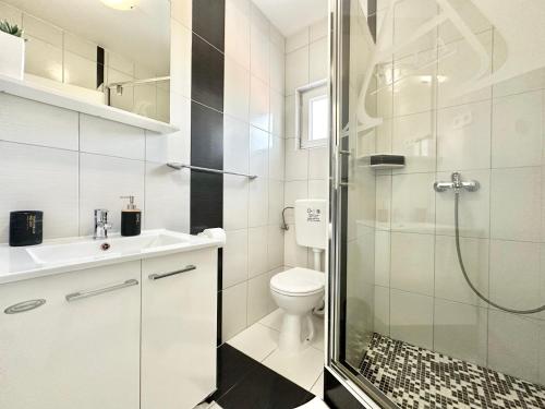 a white bathroom with a shower and a toilet at Apartments Villa A - Heating Pool in Trogir