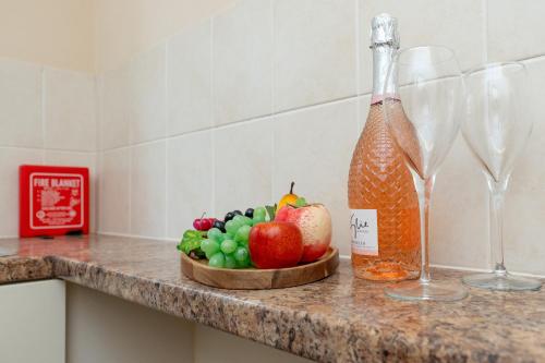 a bowl of fruit on a counter next to two wine glasses at Open Mind Property - Cozy Studio Flat in Bournemouth