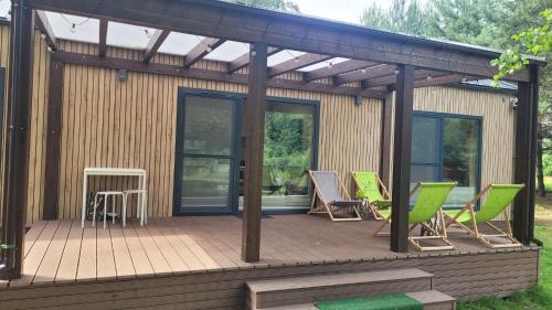 a wooden deck with lawn chairs on it at Wiosłem w Hamaku Domek nad Wkrą 
