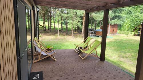 two lawn chairs on a porch with a view of a yard at Wiosłem w Hamaku Domek nad Wkrą 