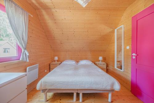 a bedroom with a bed in a wooden room at Kolorowe Domki in Pobierowo