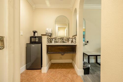 a bathroom with a sink and a refrigerator and a mirror at Hotel Avenida Victorville I 15 in Victorville