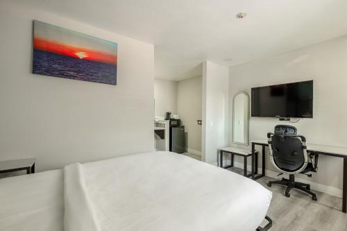 a bedroom with a bed and a desk and a television at Hotel Avenida Victorville I 15 in Victorville