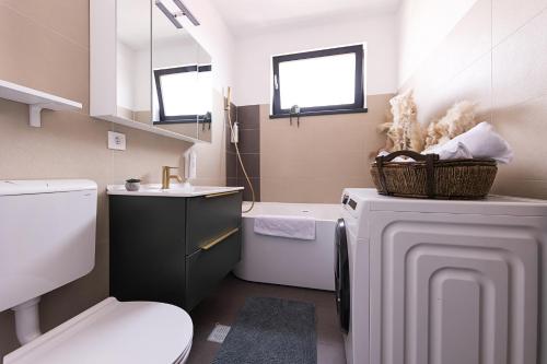 a bathroom with a toilet a sink and a washing machine at Lacul Morii Cozy Stay in Bucharest