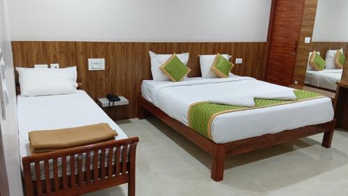 a bedroom with two beds with white sheets and green pillows at AA Residency in Tirupati
