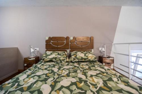 a bedroom with a bed with a green and yellow bedspread at Casa degli Specchi- Duplex in city center in Arona
