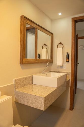 a bathroom with a sink and a mirror and a toilet at Hotel Espelho D'Água Arraial e Beach Club in Arraial d'Ajuda