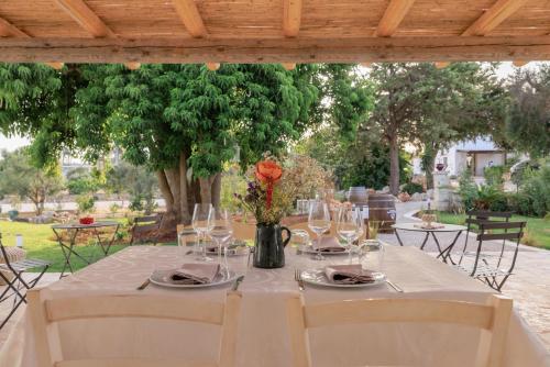 a table with glasses and a vase with flowers on it at Masseria Il Vignale in Ostuni