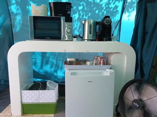 a white table with a microwave and a fan at Tenda campismo 47 A Retiro dos sonhos in Lagoa