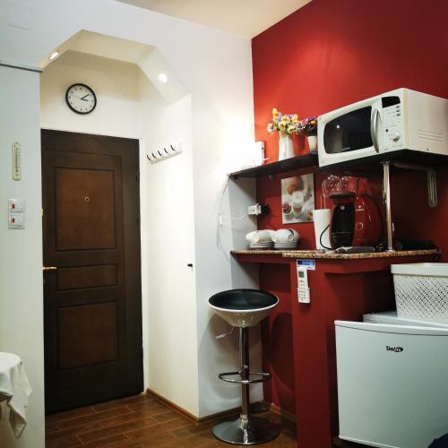 een keuken met een rode muur met een magnetron en een kruk bij Fortress Twin Room in Braşov
