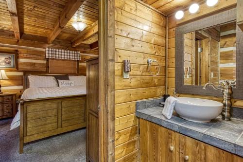 ein Bad mit einer Blockhütte, einem Waschbecken und einem Bett in der Unterkunft Laceys Place By Beyond Expectations W Hot Tub in Sevierville