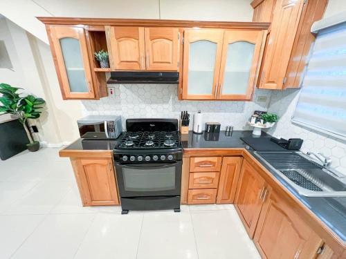 a kitchen with a stove and wooden cabinets at Stacys Place #4 Studio Apartment in Port-of-Spain
