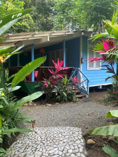 a blue house with pink flowers in front of it at Villas Itaita Beach Cabins in Punta Uva