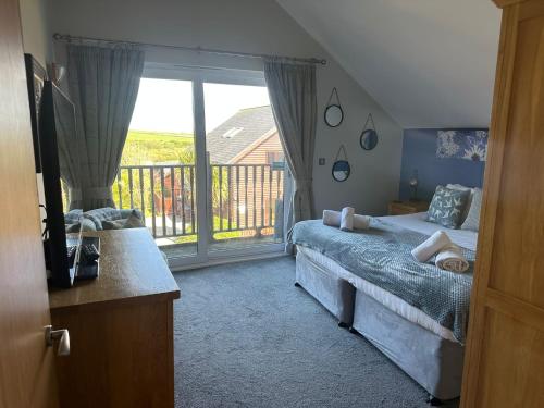 a bedroom with a bed and a large window at 5A Retallack Resort & Spa in Saint Columb Major