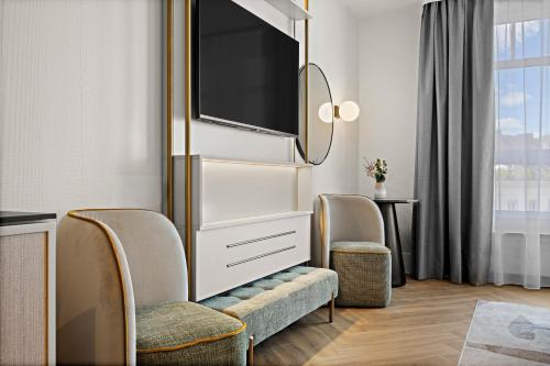 a hotel room with two chairs and a tv at Leonardo Hotel Mainz in Mainz