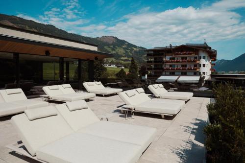 a group of white couches and tables on a patio at HELD - Hotel & Spa , 4 Sterne Superior, Zillertal in Fügen