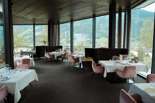 a restaurant with white tables and chairs and windows at HELD - Hotel & Spa , 4 Sterne Superior, Zillertal in Fügen