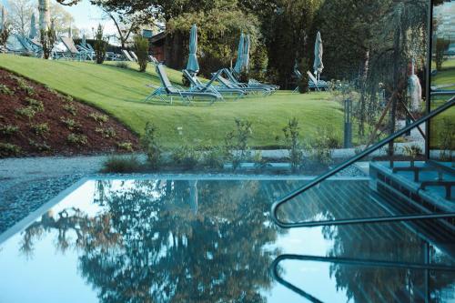 a swimming pool with chairs and a table with a reflection at HELD - Hotel & Spa , 4 Sterne Superior, Zillertal in Fügen