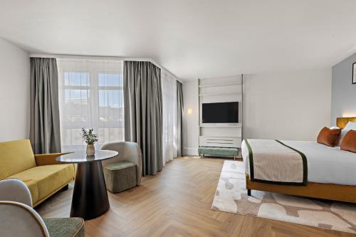a hotel room with a bed and a living room at Leonardo Hotel Mainz in Mainz