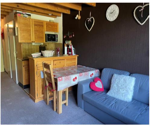 a living room with a blue couch and a kitchen at Duplex les 2 Alpes in Les Deux Alpes