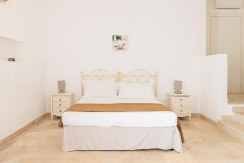 a white bedroom with a large bed and two night stands at Masseria Il Vignale in Ostuni