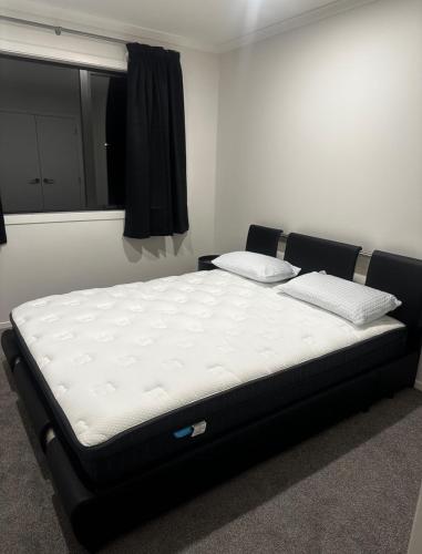 a large bed in a room with a window at Two Bedrooms With Two Bathrooms in Hamilton
