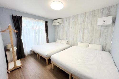 two beds in a small room with a window at グランディオーソ沖縄プールヴィラ恩納4 in Onna