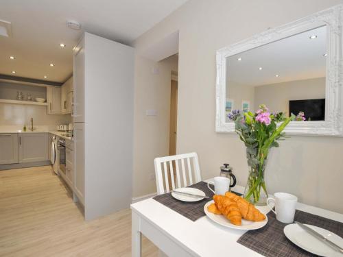 a kitchen and dining room with a table with a vase of flowers at Evelyn in Looe