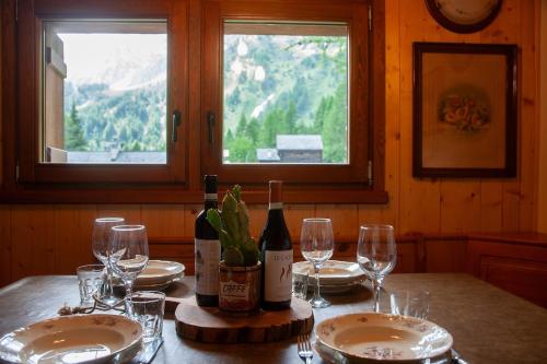 a table with two bottles of wine and glasses at Casa Cantone Devero-baita storica con balcone e giardino, posizione comoda e soleggiata- spazio biciclette in Alpe Devero