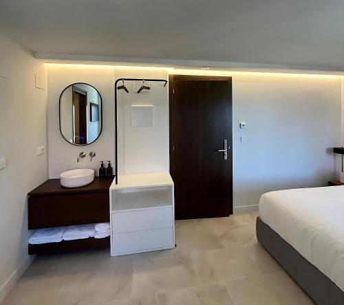 a bathroom with a sink and a bed and a mirror at Arume Rural House in Catasueiro